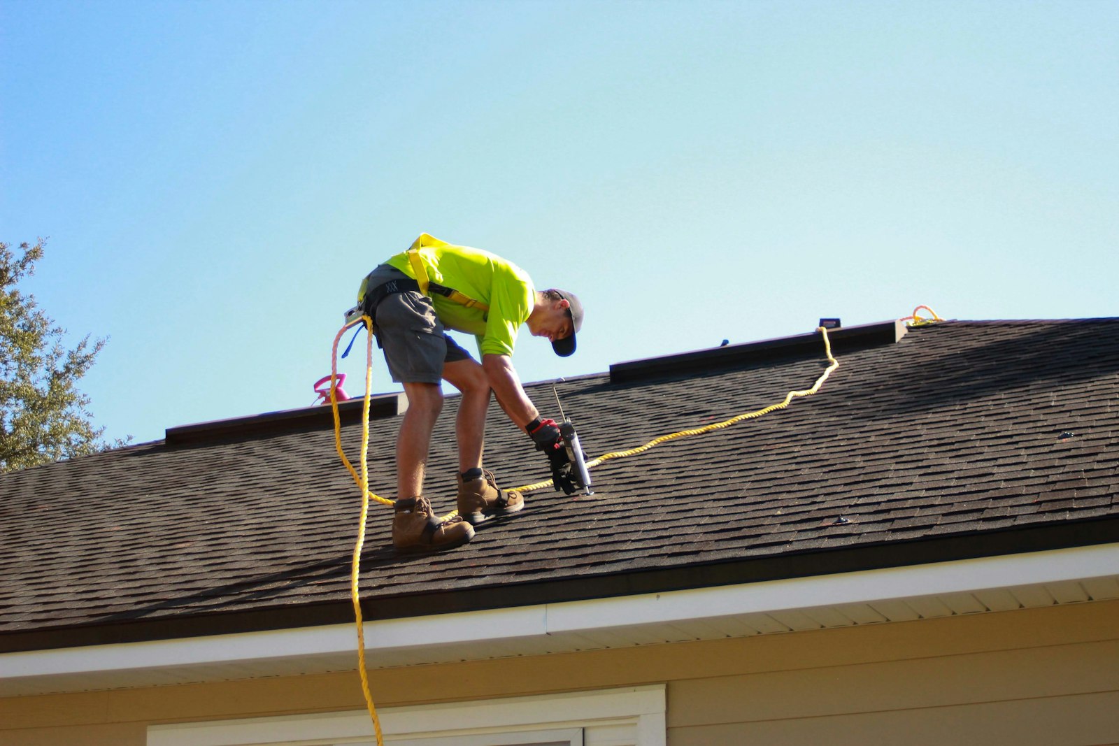Roofer inspecting asphalt shingles for leak damage